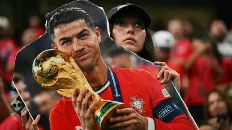 A Portugal fan holds a cardboard cutout of Cristiano Ronaldo with the World Cup trophy during the World Cup
