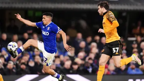 PA Media Ipswich Town's Marcelino Nunez (left), wearing a blue and white strip, and Hull City's Paddy McNair, in a gold and black strip, battle for the ball.