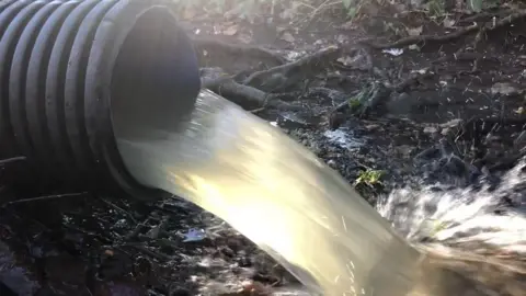 A generic image of waste water flowing out of a pipe and splashing on the open ground