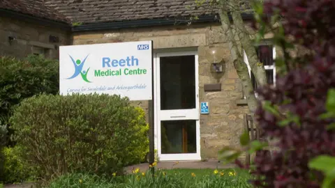 A building with a sign outside reading "Reeth Medical Centre - Caring for Swaledale and Arkengarthdale."