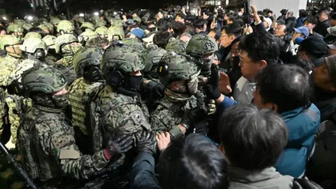 Getty Images Soldiers in full tactical uniform clash with tight crowds of people