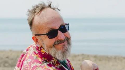 TV chef Dave Myers smiling at the camera, pictured by the beach