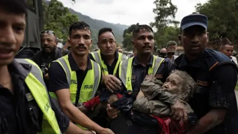Reuters Police officers carrying an elderly woman who survived the flash flood at Trishuli in Nuwakot district of Nepal