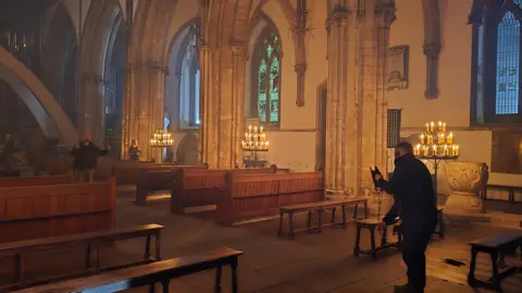 Llandaff Cathedral A film crew member inside the cathedral, let up by candles