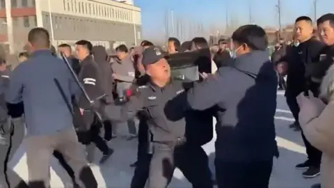 A policeman beats a protester with a baton in Pucheng, Shaanxi province in China during large scale demonstrations. Grab from video on X