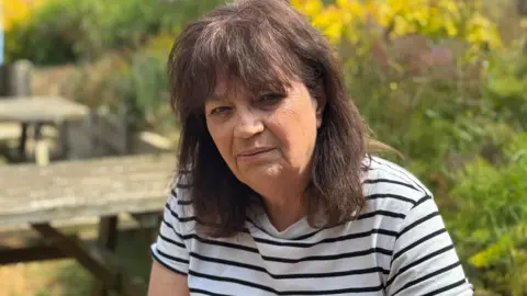George King/BBC Jenny Kirtley wearing a striped black and white t-shirt. She has dark brown hair.
