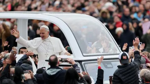 Reuters The Pope waves to worshippers from the popemobile