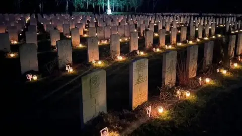 Rows of gravestones at the cemetery in Venray, with a candle lit in front of every gravestone.