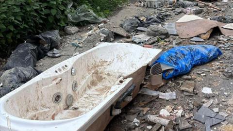 A discarded bath and other rubbish fly-tipped