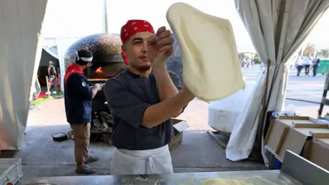 Billel Bensalem / Getty Images An image of a man tossing a pizza in Algiers, Algeria - Monday 5 August 2024