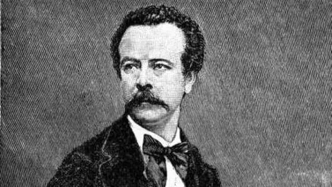 A black and white photograph of Charles Worth, aged 30. He is sitting for an official portrait and is wearing a dark coloured frock coat with a light coloured waistcoat and a black cravat. 