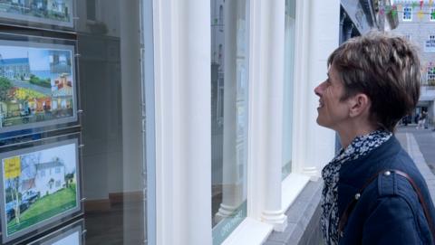 Woman looking at estate agent window 