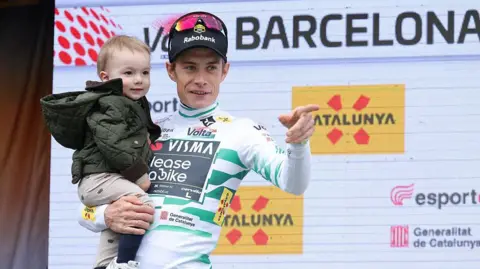 Jonas Vingegaard holds his young son on the podium after his victory