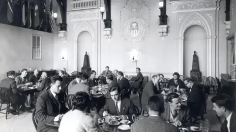 A black and white photo of a dinner banquet inside a 16th Century property. 