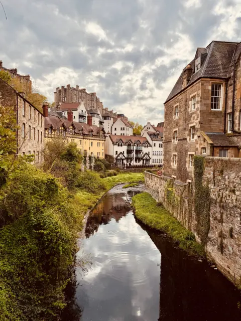 Paul Le Combre A picture showing a river running through a town, with houses on either side