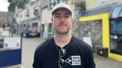 A man wearing a black top and pink hat