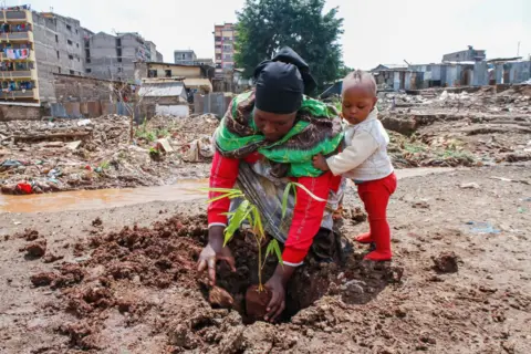 Boniface Muthoni/Getty Images A Kenyan mother and her son plant a tree