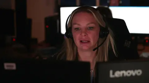 A female Devon and Cornwall police call handler sitting at her desk with a headset on