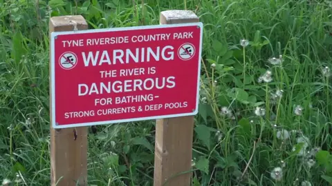 Sign saying: Warning the river is dangerous for bathing
