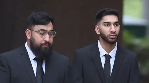 Mohammed Fahir Amaaz and Muhammad Amaad arrive at Liverpool Crown Court. Both are wearing black suits and ties.