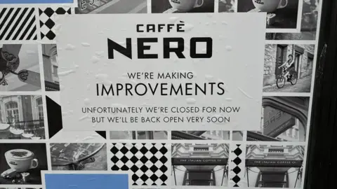 A sign on the window of the cafe in Lombard Street in black writing with a white background. It says:  'We're making improvements. Unfortunately, we're closed for now but we'll be back open very soon."