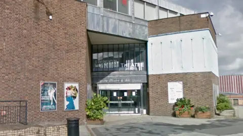 Google Exterior view of the Wyvern Theatre, with a predominantly brick frontage with large glass door and windows at the front 