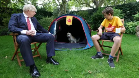 Number 10 Downing Street Boris Johnson and Max Woosey look into tent as Dilyn the dog looks back out