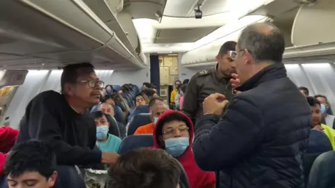 Gustavo Petro, wearing a blue jacket and facing away from the camera, speaks to migrants who were deported from the US on board a Colombian air force plane