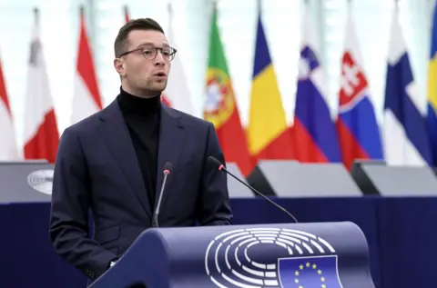 EPA Bardella speaks while wearing a dark turtleneck and suit in front of European flags, at the European Parliament in October.