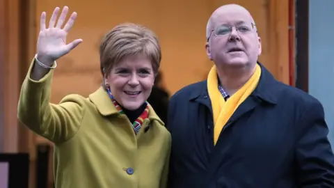 PA Media Nicola Sturgeon and Peter Murrell standing side by side in overcoats.