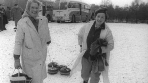 Two women holding curling equipment