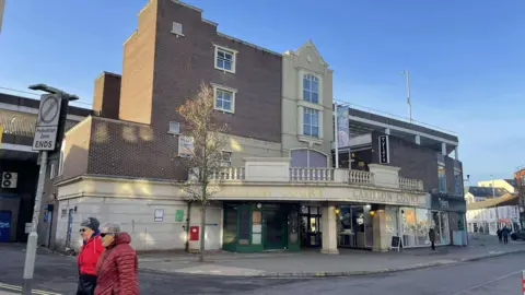 An entrance to the Carillon Court shopping centre from the rear, showing a glimpse of the car park on the roof too