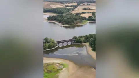 Aerial view of a stone railway viaduct crossing a low reservoir