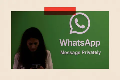 Reuters A woman uses her phone next to a logo of the WhatsApp 