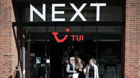 Three women walk out of a Next shop