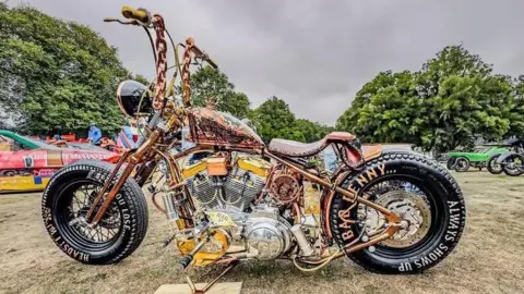 Hornsea Bike Show A gold-coloured motorcycle with ornate detailing on the frame. The tyres have writing on them including the words: "Bad penny, always shows up."