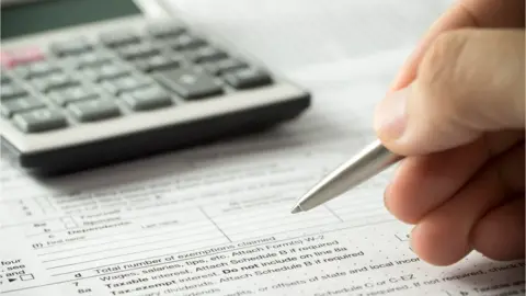 Getty Images Person filling out a form with a calculator