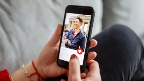 A woman holding a phone using a dating app 