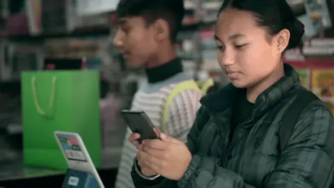 A young woman using her phone to scan a QR code in India