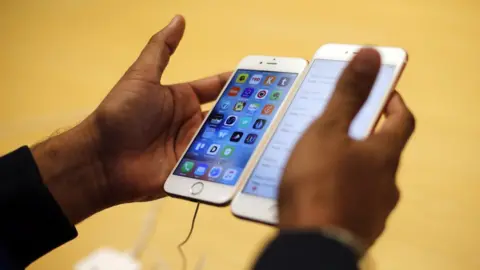 Associated Press Man holding two new iPhones