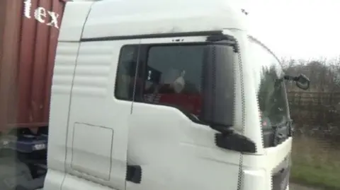 Handout A HGV driver is seen putting up his middle finger while driving.