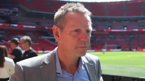 Jack Valpy/BBC Stuart Pearce standing by the pitch at Wembley wearing a grey suit.
