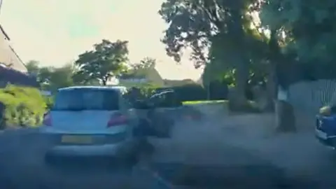 South Yorkshire Police A blurred CCTV image of a silver car stopped on a residential street with the driver's side door open.