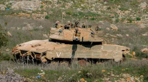 AFP An Israeli military tank manoeuvres on grassy terrain near the southern Lebanese border town of Blida on 2 February 2025