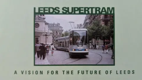 Metro Promotional image of a tram travelling through Leeds, with the wording "Leeds Supertram - A Vision for the Future of Leeds".