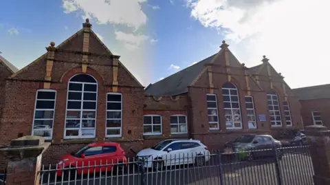 Google Victorian school building with three cars parked outside