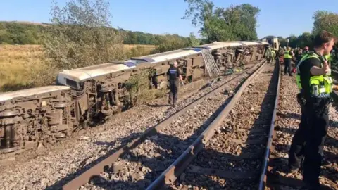 John May A number of the carriages which derailed tumbled into a field next to the railway