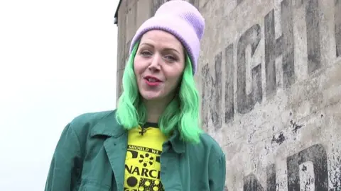 A woman in front of a ghost sign