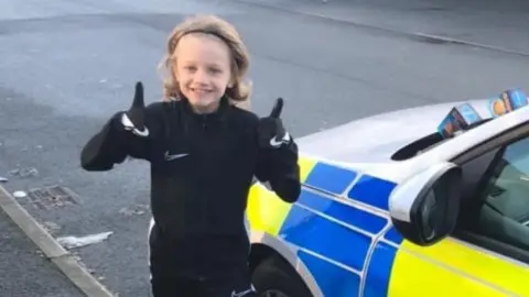 Family handout Jordan Banks next to a police car