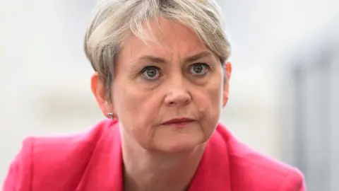 Reuters Yvette Cooper, who has cropped blonde hair, looks on during a visit to a library